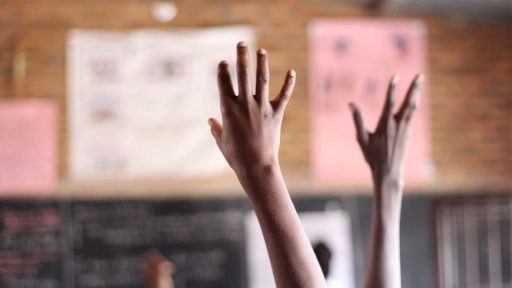 student hand raised in a classroom in Rwanda
